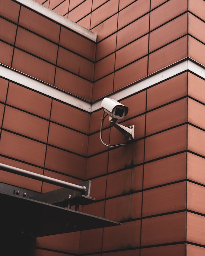 Security camera monitoring a red brick building exterior, symbolizing modern surveillance in Germany.
